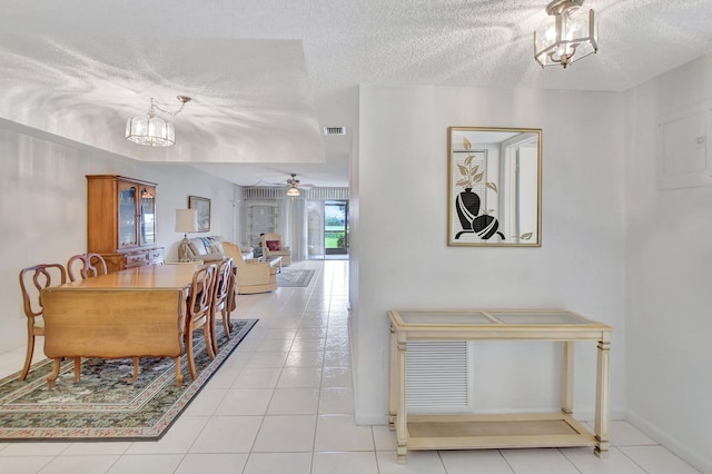 dining area with light tile patterned flooring, ceiling fan with notable chandelier, and a textured ceiling