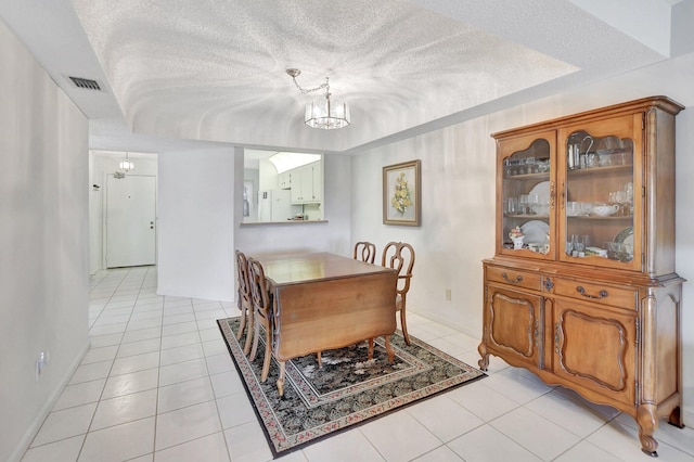 dining area with an inviting chandelier, a textured ceiling, and light tile patterned flooring