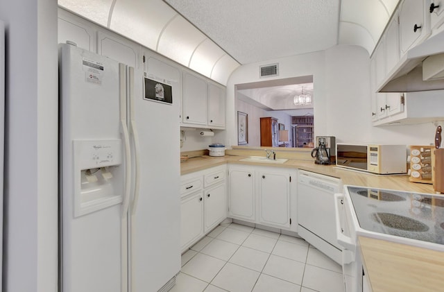 kitchen with white appliances, sink, white cabinetry, an inviting chandelier, and a textured ceiling