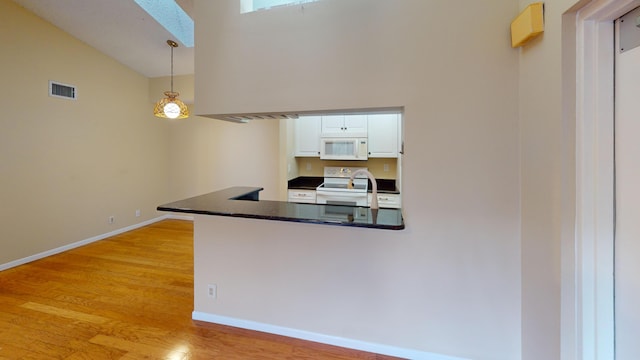 kitchen with kitchen peninsula, white appliances, pendant lighting, light hardwood / wood-style floors, and white cabinetry