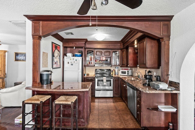 kitchen with appliances with stainless steel finishes, dark hardwood / wood-style flooring, a textured ceiling, ornamental molding, and sink