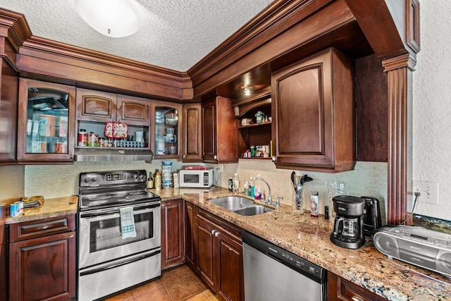 kitchen featuring light stone counters, a textured ceiling, sink, appliances with stainless steel finishes, and light tile patterned floors