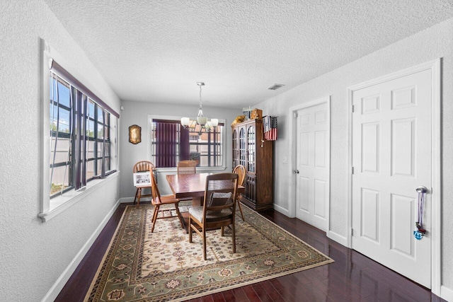 dining room featuring an inviting chandelier, a textured ceiling, and dark wood-type flooring