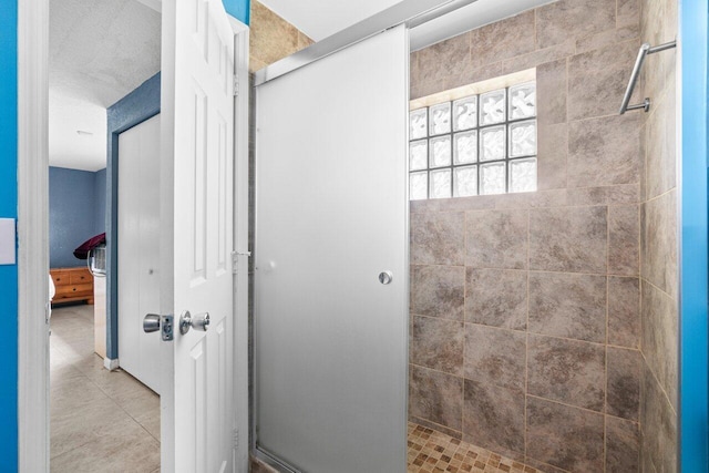 bathroom featuring a textured ceiling, a tile shower, and tile patterned floors