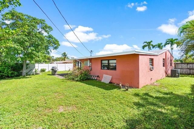 back of property with cooling unit, central AC, and a yard