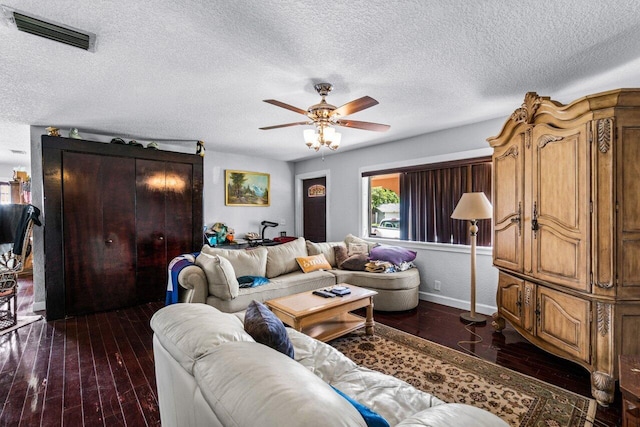 living room with ceiling fan, a textured ceiling, and dark hardwood / wood-style floors