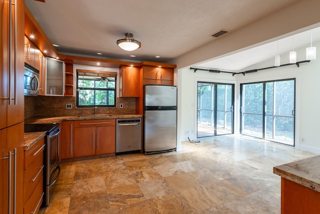 kitchen featuring lofted ceiling, decorative backsplash, sink, decorative light fixtures, and appliances with stainless steel finishes