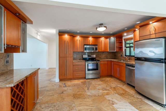 kitchen featuring sink, decorative backsplash, light stone counters, and stainless steel appliances