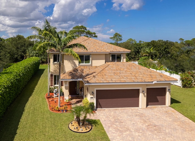 mediterranean / spanish home featuring a front yard and a garage