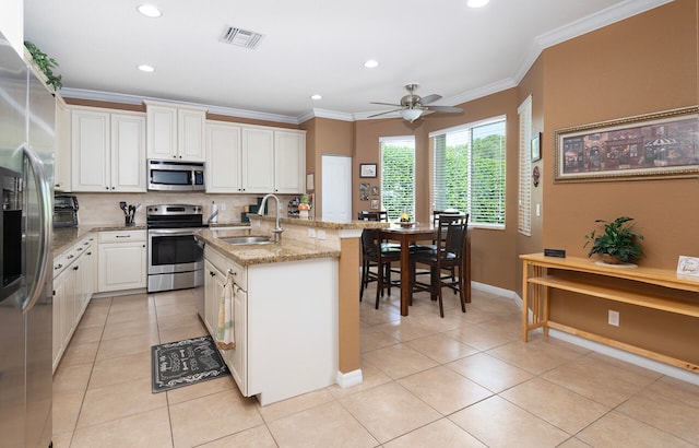 kitchen with appliances with stainless steel finishes, white cabinetry, an island with sink, ceiling fan, and sink