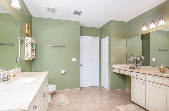 bathroom with vanity, toilet, a textured ceiling, and tile patterned floors