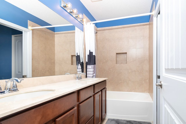 bathroom with a textured ceiling, vanity, and shower / bath combo with shower curtain