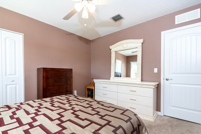 bedroom featuring a textured ceiling, light carpet, ceiling fan, and a closet