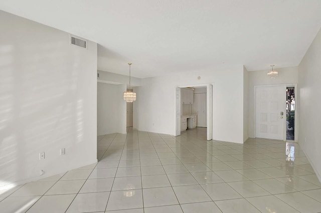 unfurnished room featuring light tile patterned floors and a chandelier