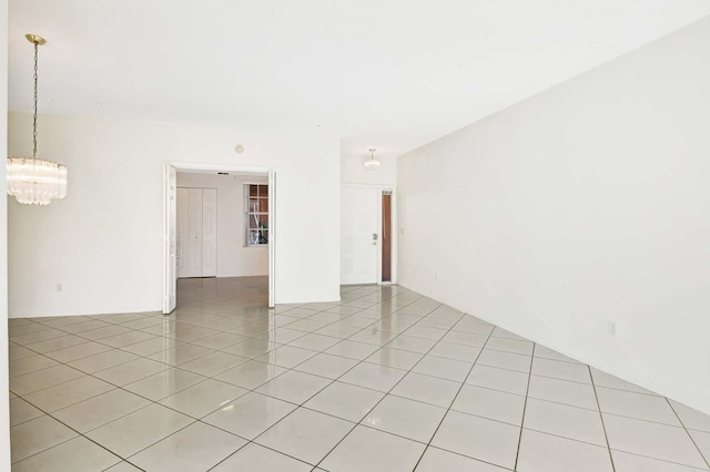 empty room with light tile patterned floors and an inviting chandelier