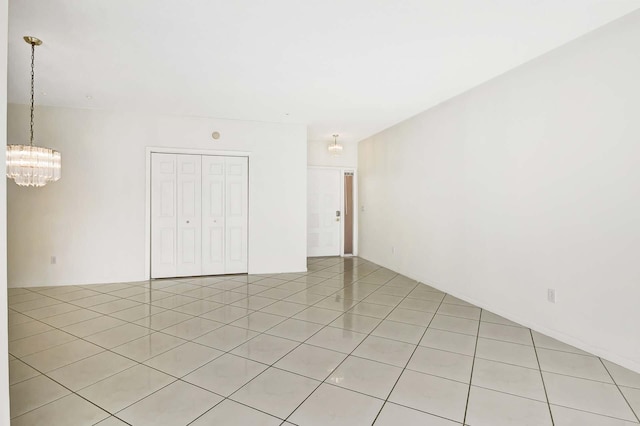 tiled empty room with a notable chandelier