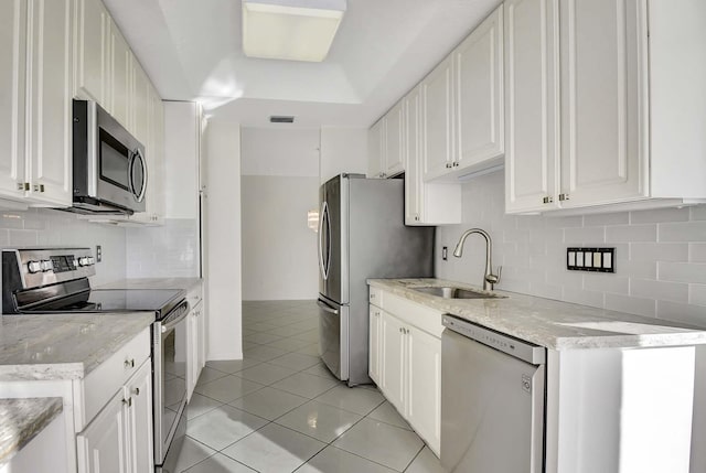 kitchen with appliances with stainless steel finishes, tasteful backsplash, sink, light tile patterned floors, and white cabinetry