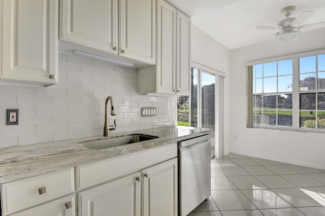 kitchen with backsplash, stainless steel dishwasher, sink, light tile patterned floors, and white cabinetry