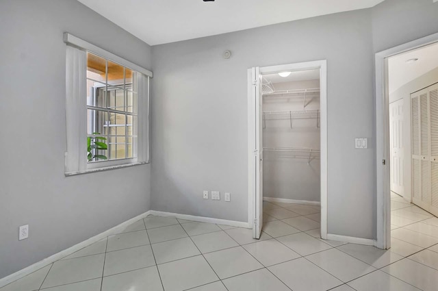 unfurnished bedroom with light tile patterned floors, a walk in closet, and a closet