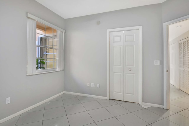 unfurnished bedroom featuring light tile patterned floors and a closet