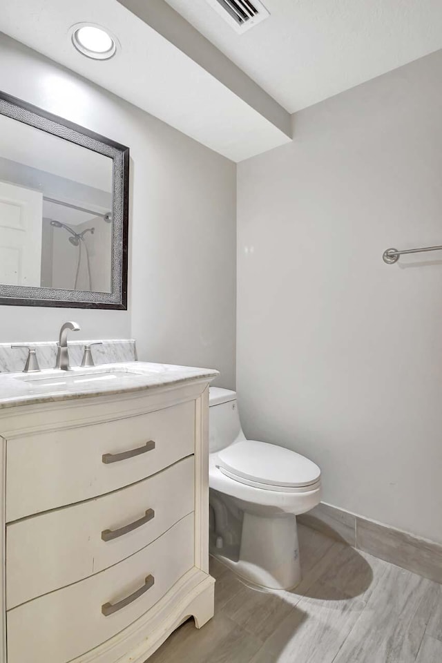 bathroom with wood-type flooring, vanity, toilet, and walk in shower