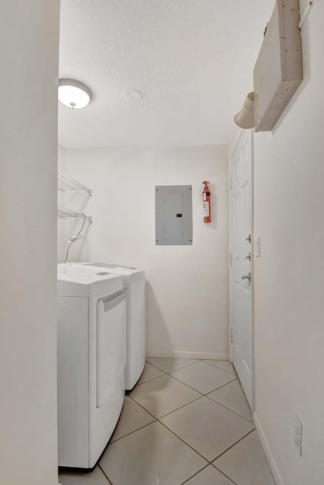 washroom featuring washer and dryer, light tile patterned floors, a textured ceiling, and electric panel