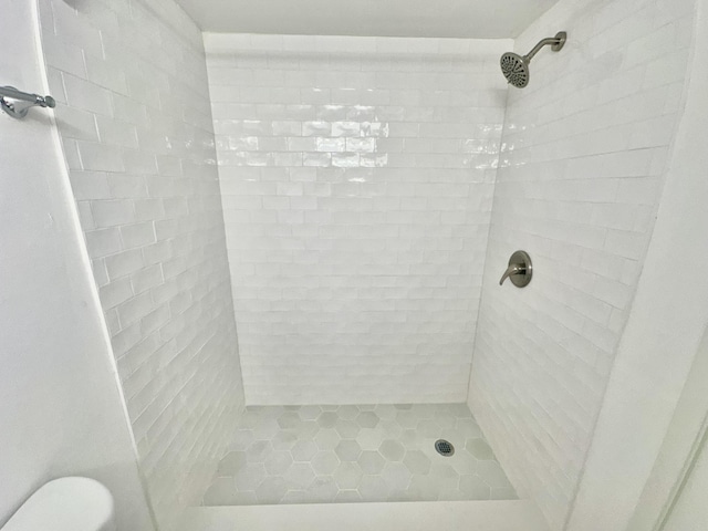 bathroom with a tile shower and toilet