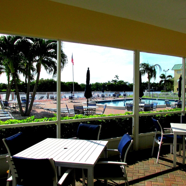 view of patio with outdoor dining area, fence, and a community pool