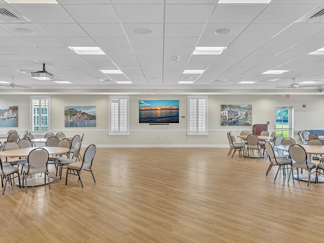 dining area featuring ceiling fan, a drop ceiling, and light wood-type flooring