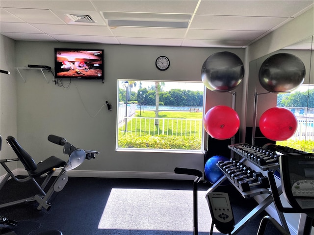 exercise room featuring a paneled ceiling, visible vents, and baseboards