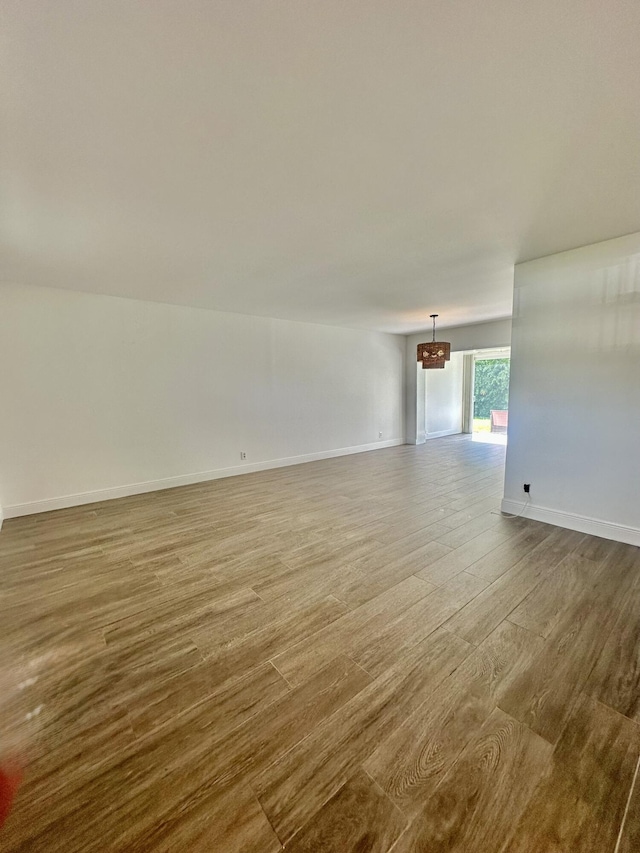 unfurnished room featuring dark wood-style floors, baseboards, and a notable chandelier