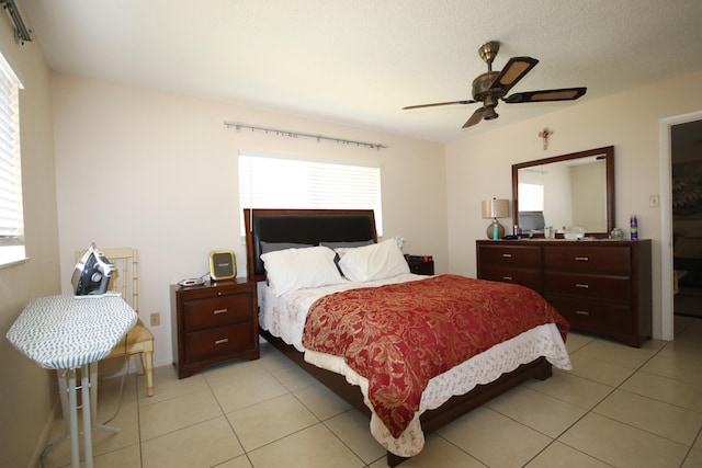 bedroom with a textured ceiling, light tile patterned floors, and ceiling fan