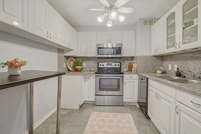 kitchen featuring appliances with stainless steel finishes, backsplash, sink, and white cabinets