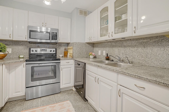 kitchen with white cabinets, stainless steel appliances, sink, and tasteful backsplash