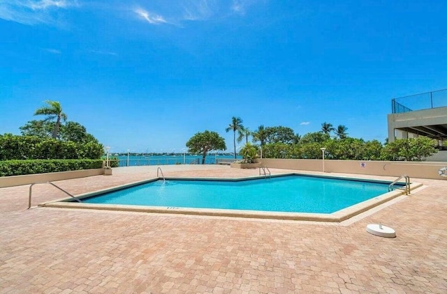 view of pool with a water view and a patio area