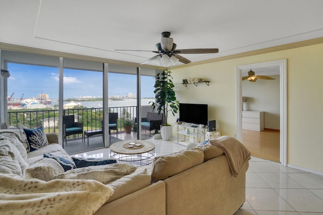 tiled living room with ceiling fan, floor to ceiling windows, and ornamental molding