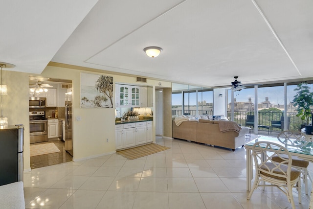 tiled living room with floor to ceiling windows and ceiling fan