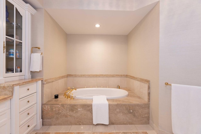 bathroom featuring tiled tub, vanity, and tile patterned flooring