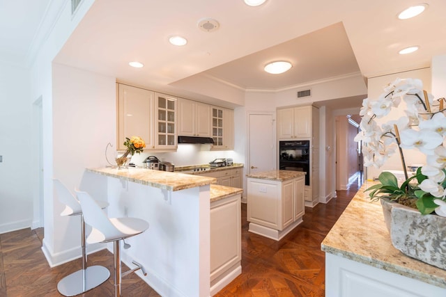 kitchen featuring light stone counters, kitchen peninsula, white cabinetry, stainless steel gas stovetop, and a center island