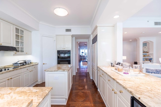 kitchen with white cabinets, cooktop, crown molding, light stone countertops, and dark parquet floors