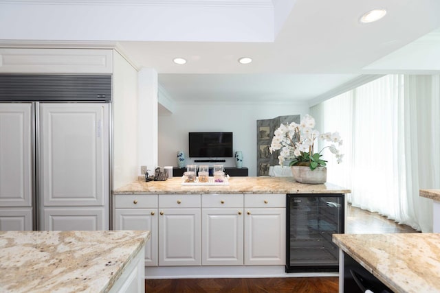 kitchen featuring light stone counters, white cabinets, beverage cooler, and paneled fridge