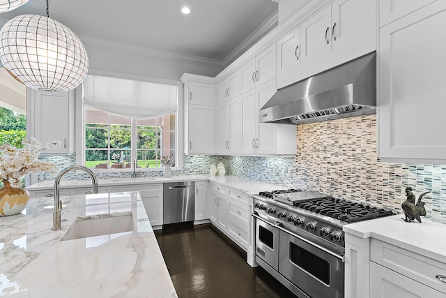 kitchen with hanging light fixtures, sink, white cabinetry, wall chimney range hood, and stainless steel appliances