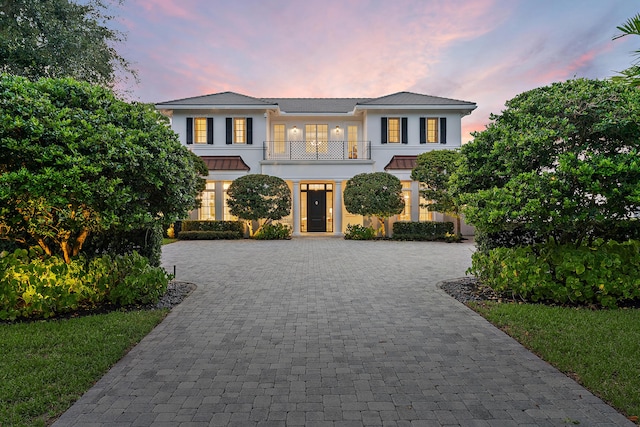 view of front of house with a balcony, decorative driveway, and stucco siding