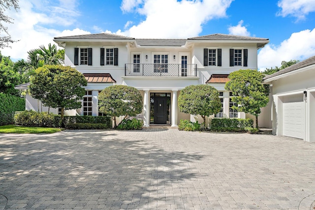 view of front of home featuring decorative driveway, a balcony, and stucco siding