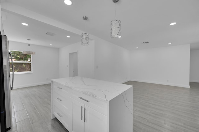 kitchen featuring light hardwood / wood-style floors, stainless steel refrigerator, a kitchen island, hanging light fixtures, and white cabinets