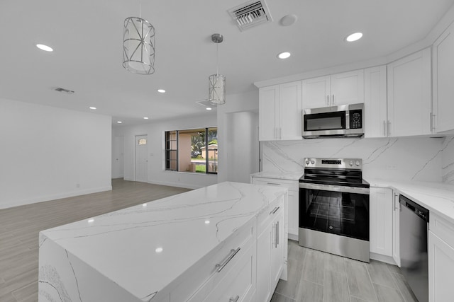 kitchen featuring pendant lighting, appliances with stainless steel finishes, light hardwood / wood-style flooring, and white cabinetry