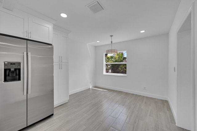 kitchen with white cabinets, light wood-type flooring, pendant lighting, and stainless steel fridge with ice dispenser