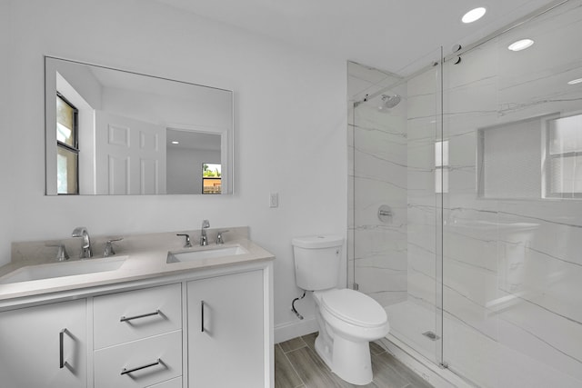 bathroom featuring a shower with door, vanity, and toilet