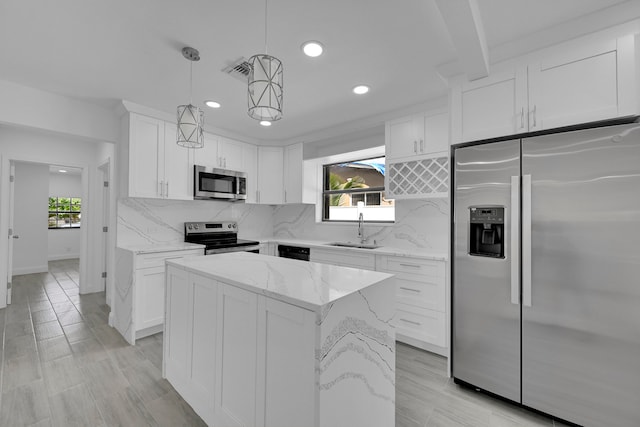 kitchen featuring backsplash, stainless steel appliances, hanging light fixtures, white cabinets, and a center island