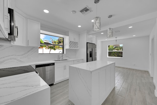 kitchen featuring pendant lighting, sink, appliances with stainless steel finishes, a center island, and white cabinetry